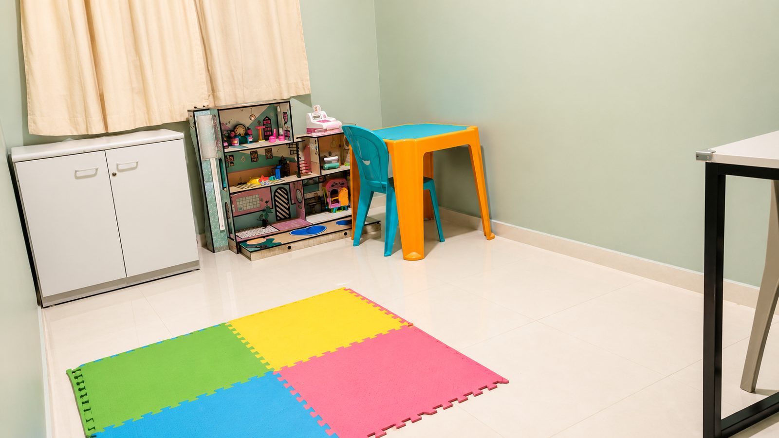 Sala infantil com tapete colorido, casa de bonecas e mesinha