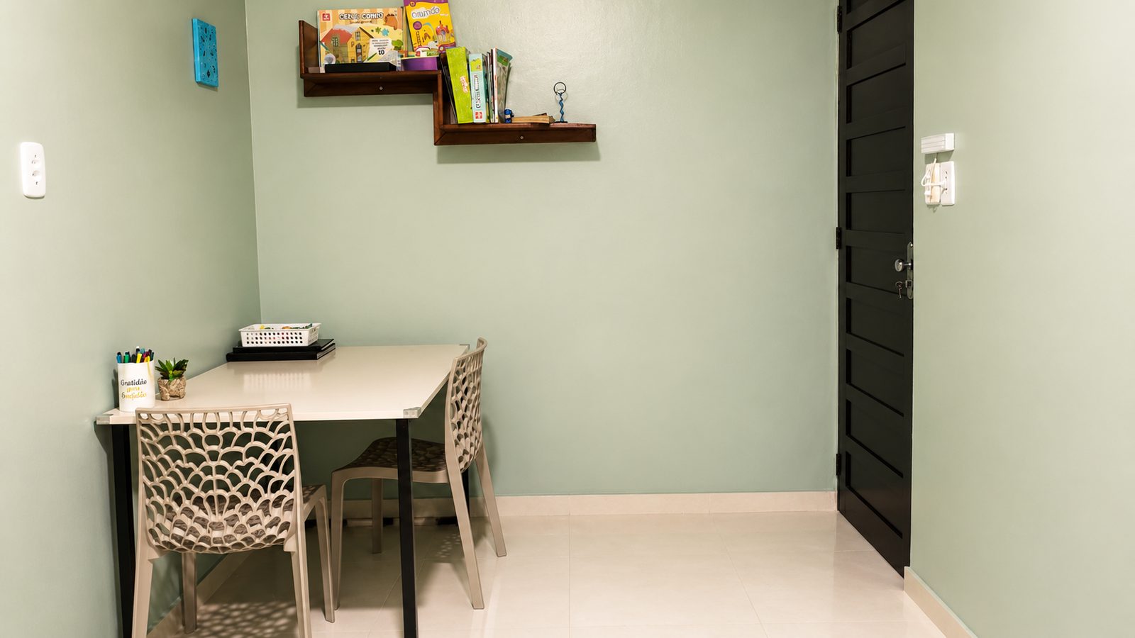 Sala de atendimento com mesa, cadeiras e prateleira com jogos